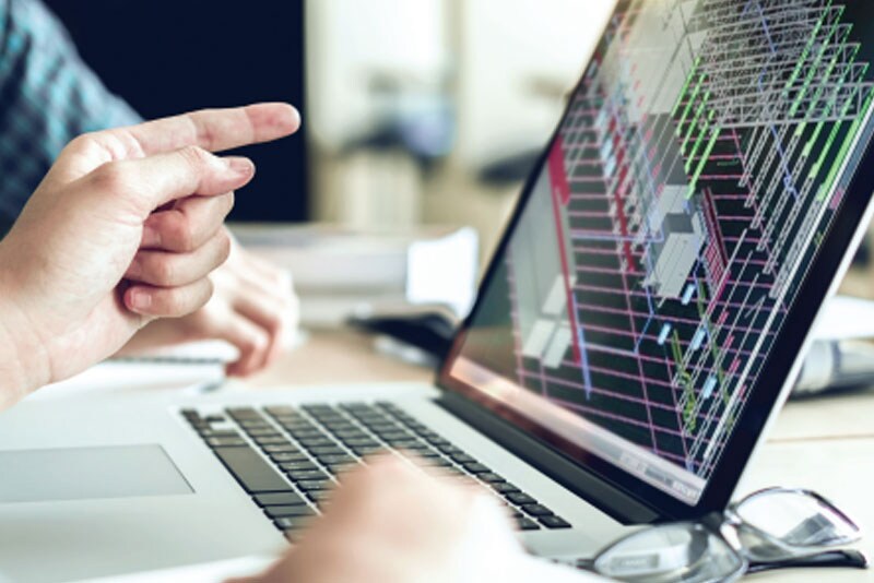 A laptop on a desk with a finger pointing at a screen