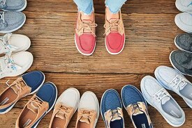 A pair of human legs and feet surrounded by pairs of shoes forming a circle