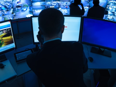 Back view of a man sitting, looking at a desktop monitor